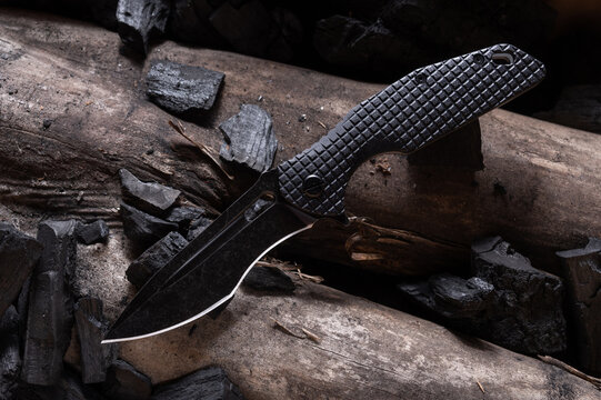Knife with a curved blade. Black knife on a log.