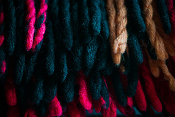 Cold season home warmth and cosiness. Woolen braided thick threads tassels of a warm traditional plaid background.