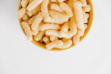 Corn sticks in a yellow bowl on a white background. Top view. Place for your text
