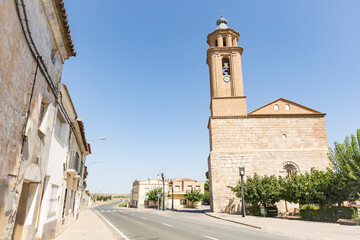Fototapeta na wymiar a paved road passing through Candasnos town with Our Lady of the Assumption church in the foreground, province of Huesca, Aragon, Spain
