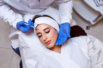 Beautiful woman getting lifting injection in forehead. Close-up woman hyaluronic acid injection. Botox Injections of skin rejuvenation. Cosmetic procedures, botox injections, hyaluronic acid.