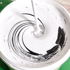 Handyman makes gray color while mixes black and white using drill.