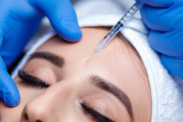 Beautiful woman getting lifting injection in forehead. Close-up woman hyaluronic acid injection....