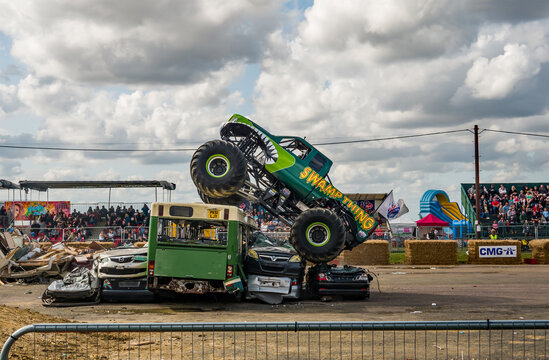 Podington, Bedfordshire, UK – August 18 2019. An Illustrative Photo Of  The Monster Truck Swamp Thing Jumping Over Some Scrap Cars During A Public Demonstration