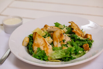 Plato de ensalada fresca con lechuga, pollo, queso y semillas frescas con salsa