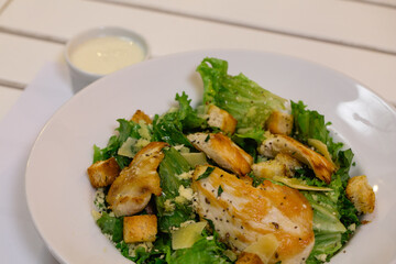 Plato de ensalada fresca con lechuga, pollo, queso y semillas frescas emplatado con salsa