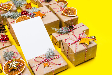 Naklejka na ściany i meble New year postcard mockup with many presents and christmas decor on yellow background. Holiday packaging border with pine tree branch, wrapped paper boxes. Greetings template