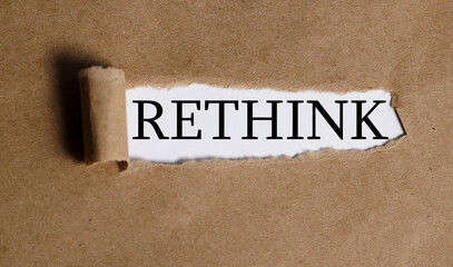 RETHINK, text on white paper on torn paper background