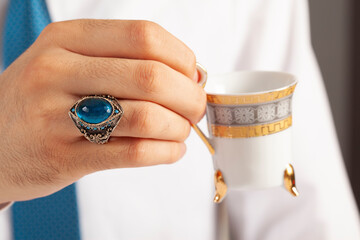 Blue silver ring and accessories on male finger in white shirt with blue tie.