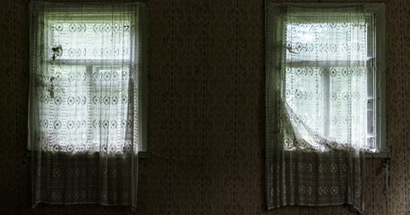 old dirty white curtains hanging on aged wooden window frames in abandoned village house