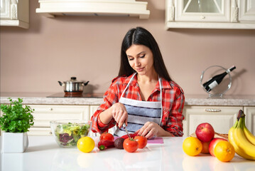 girl at the kitchen table cuts vegetables and fruits