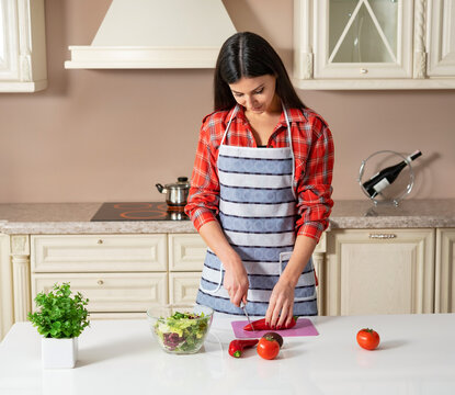 girl in the kitchen slices a vegetable salad