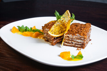 Close up on a portion of gourmet tiramisu Italian dessert topped with a sprig of mint served on a plate at table in a side view