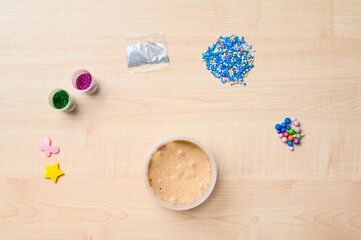 The concept of making slime at home. A slime in a plastic jar is on the table next to the ingredients for decoration.