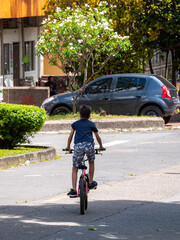 Young Latin Boy Rides a Red Bike down a Paved Street