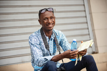 young tourist photographer holding a bottle of water and map