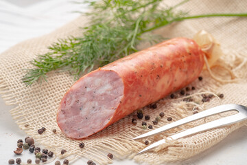 Large smoked salami sausage cut in half on rustic background