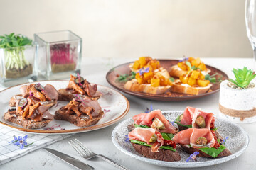 Bruschetta with prosciutto and various ingredients on plates served on the table