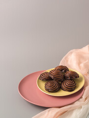 Traditional Russian vanilla marshmallows in chocolate glaze in pink and yellow plates on gray background. Vertical. Copy space
