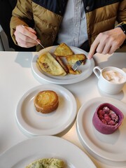 Breakfast for two: scrambled eggs, hash browns, black coffee, cappuccino, dessert