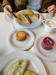 Breakfast for two: scrambled eggs, hash browns, black coffee, cappuccino, dessert