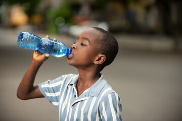 Fototapeta na wymiar pretty little boy drinking water in a plastic bottle