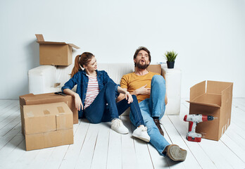 Fototapeta na wymiar Man and woman in the room on the floor renovation work moving and boxes of tools