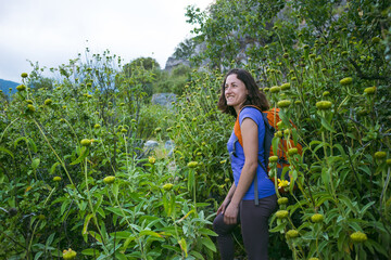 A woman with a backpack goes along the path through the tall grass
