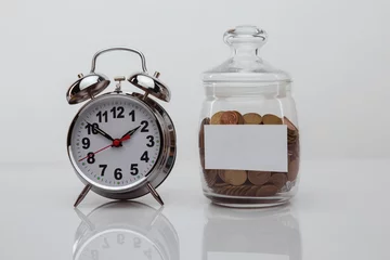 Fotobehang Coins in a bank with space for text and alarm clock. Time is money concept. © burdun