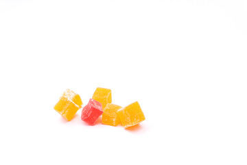 Several cubes of yellow and one red Turkish delight on a white background