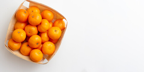 Ripe citrus fruits: tangerines in a wicker basket on a white background. Space for text.
