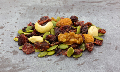 Small portion of seeds, nuts and fruit on a gray background side view.