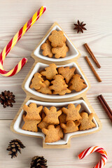 top view of plate with gingerbread cookies, a dish shaped like christmas tree on white wooden table, flat lay of three-section appetizer xmas plate close up