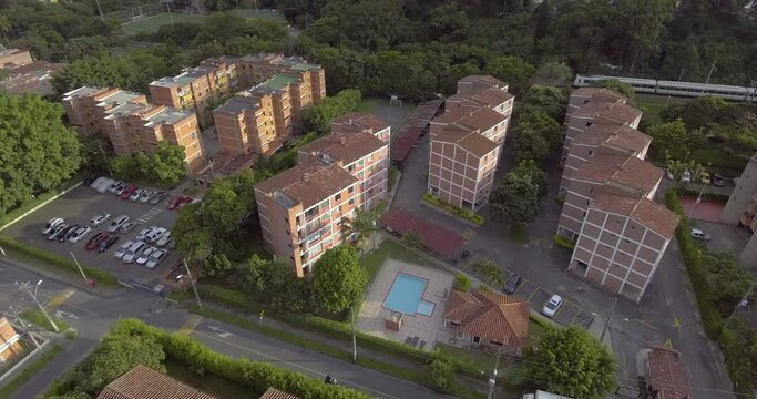 Residential Buildings, Subway Passing, Parking Lot, Pool and Trees on a Cloudy Day