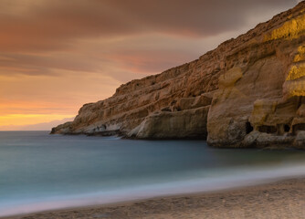 Sunset next to the roman catacombs carved on the sandstone cliffs above the Matala Beach, Crete, Greece. In Roman times, the dead were buried in them, later they were used by the first Christians
