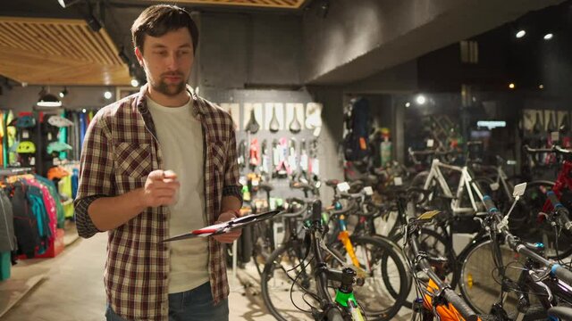 Young Caucasian male seller holding presentation of bicycles goods to buyer, first-person view, professional store of sporting travel goods. Buying equipment and quality service from professionals