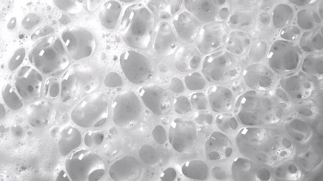 White foam with bubbles texture, soap, detergent or shampoo or cleanser surface, macro shot. Body care concept.