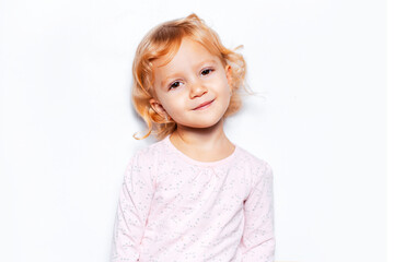 Studio portrait of child girl with curly blonde hair on background of white color.