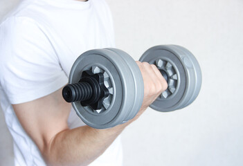 A man's hand is holding a dumbbell. Sports at home.