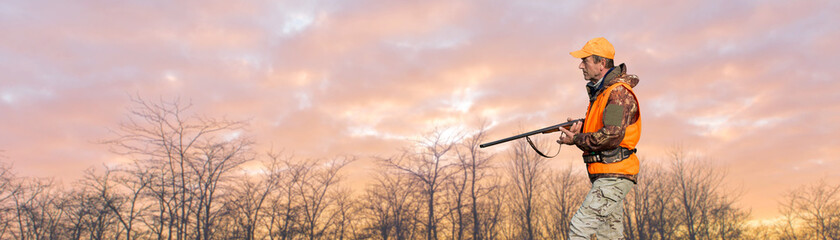 Silhouette of a hunter with a gun against the sun, an ambush for ducks.