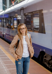 Young woman on the platform waiting for the train. Beautiful girl at the train station. Travel by train. Railway station in Bydgoszcz. Poland.