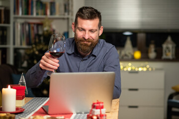 portrait of handsome man spending Christmas eve at home with laptop