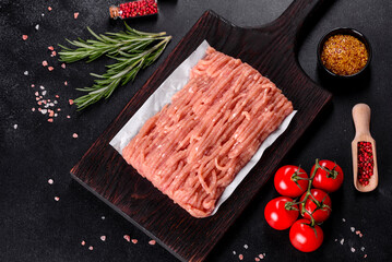 Fresh raw chicken mince on a dark wooden cutting board