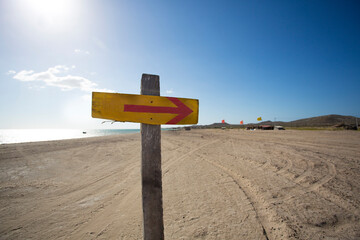 Wooden sign with an arrow and the beach in the background
