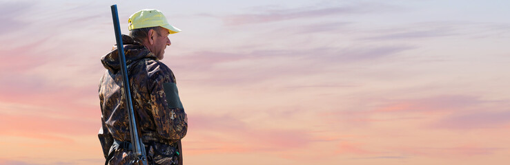Silhouette of a hunter with a gun against the sun, an ambush for ducks.
