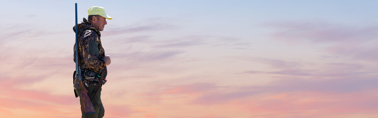 Silhouette of a hunter with a gun against the sun, an ambush for ducks.