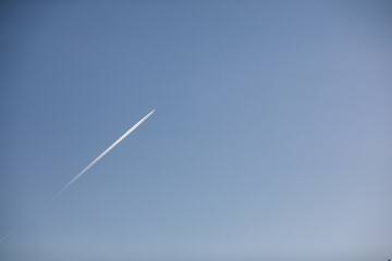 Fototapeta na wymiar airplane contrail against clear blue sky