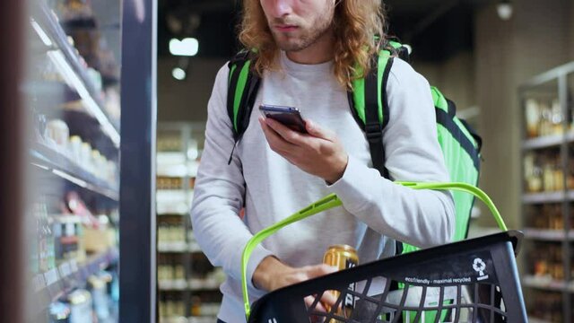 Modern courier handsome man choosing alcohol beer botttles searching goods for customer order online shopping at grocery store.