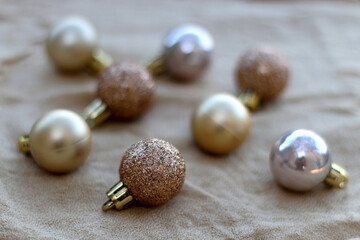 Gold Christmas baubles on beige fabric. Selective focus. 