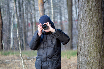 a male photographer in black clothes looks at the camera lens